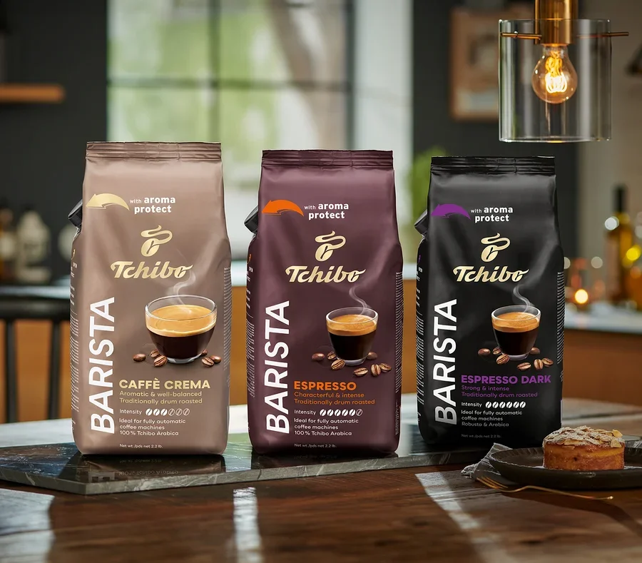 Tri balenia zrnkovej kávy Tchibo Barista stoja na stole, zľava doprava: Caffè Crema, Espresso a Espresso Dark.