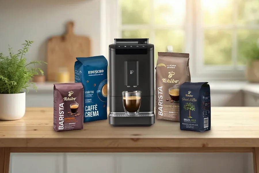 Na stole stojí kávovar, šálek espressa, Tchibo Barista Espresso, Eduscho Kräftig Caffè Crema a Tchibo Brazil Mild.
