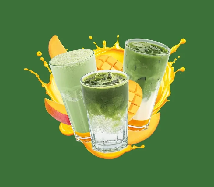 Tri poháre so zelenými nápojmi, plátkami manga a žltou špliechancou. Ľavý pohár obsahuje svetlozelené smoothie, stredný a pravý pohár vrstvené ľadové zelené nápoje.