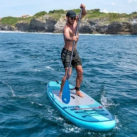 Muž vesluje na modrom paddleboarde Aqua Marina »Beast« 10'6" na mori.