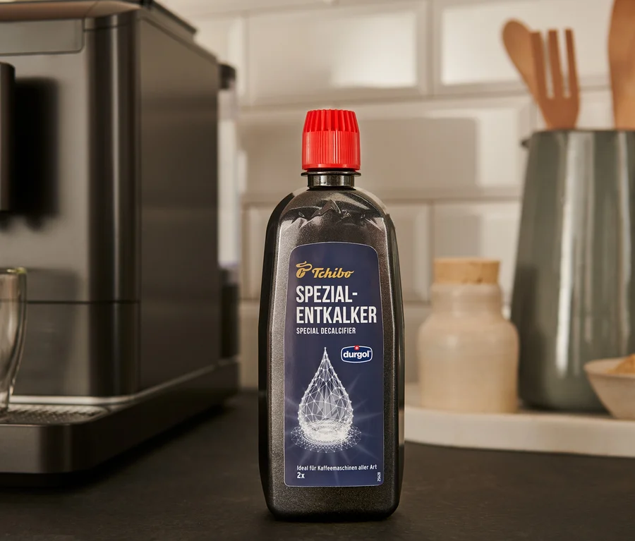 Čierna fľaša odvápňovača durgol® špeciálny odvápňovač, 400 ml stojí na linke vedľa kávovaru.
