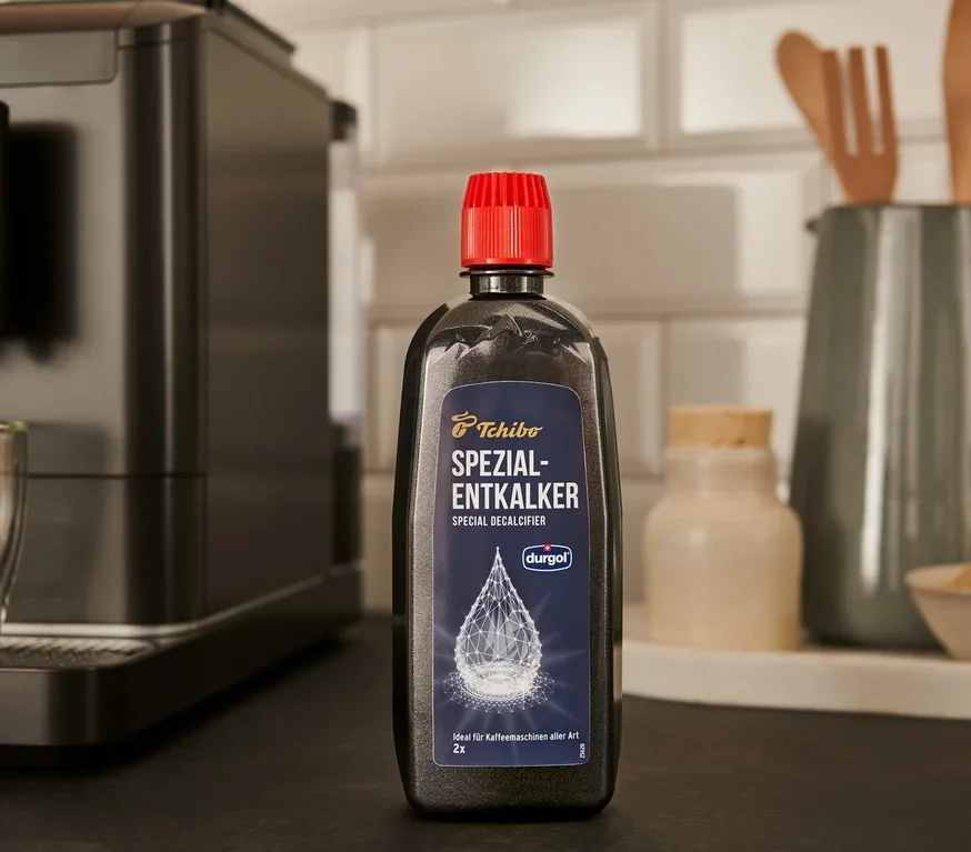 Čierna fľaša odvápňovača durgol® špeciálny odvápňovač, 400 ml stojí na linke vedľa kávovaru.