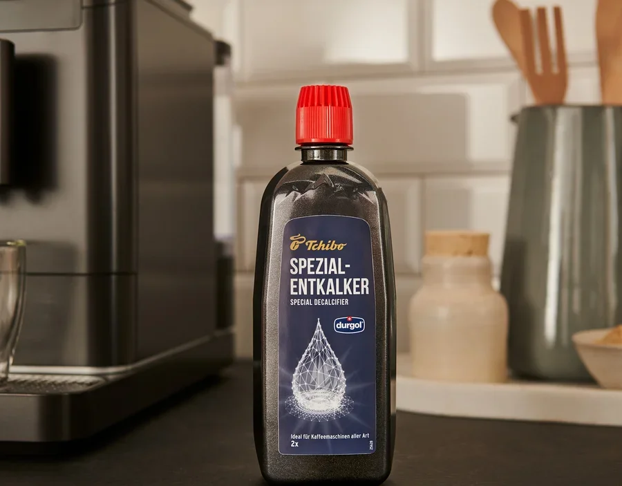 Čierna fľaša odvápňovača durgol® špeciálny odvápňovač, 400 ml stojí na linke vedľa kávovaru.