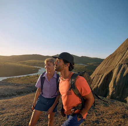 Dvaja turisti s outdoorovými batohmi a oblečením na skalnatom teréne.