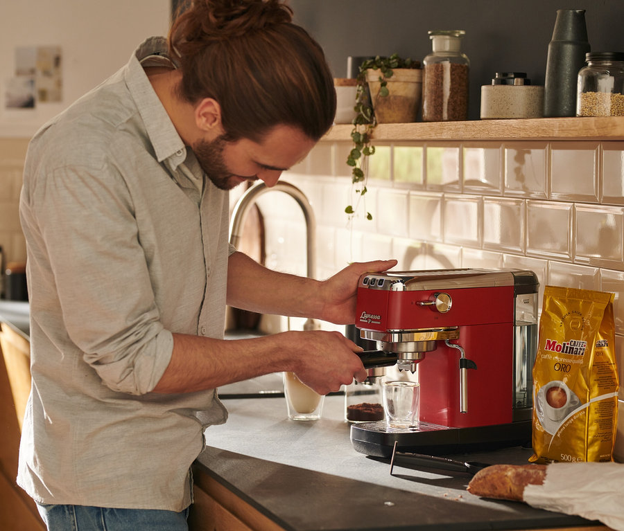 Muž používa červený pákový kávovar »Lapressa« na prípravu kávy.