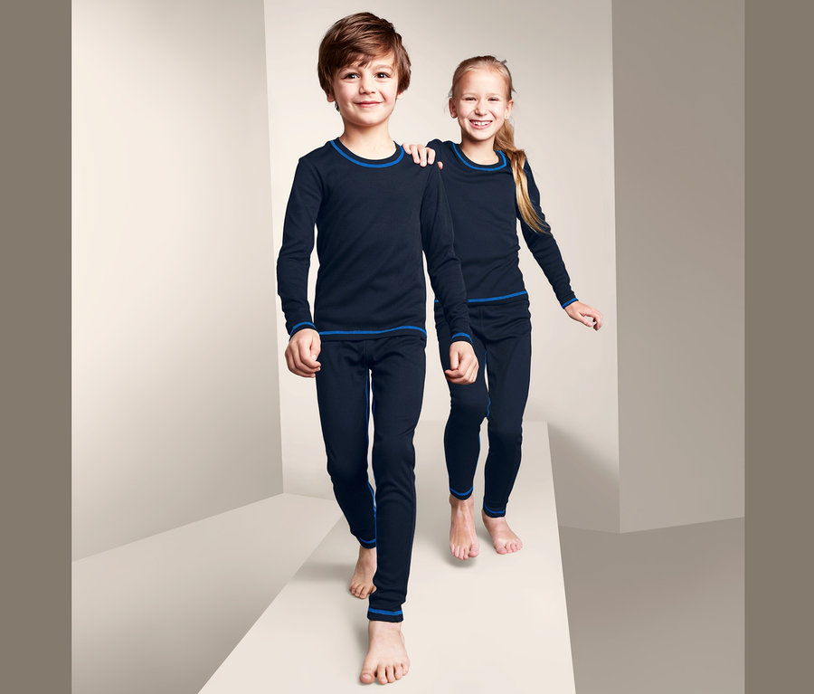 Dve deti v funkčnej spodnej bielizni tmavej modrej farby s modrým lemovaním kráčajú po bielej plošine.