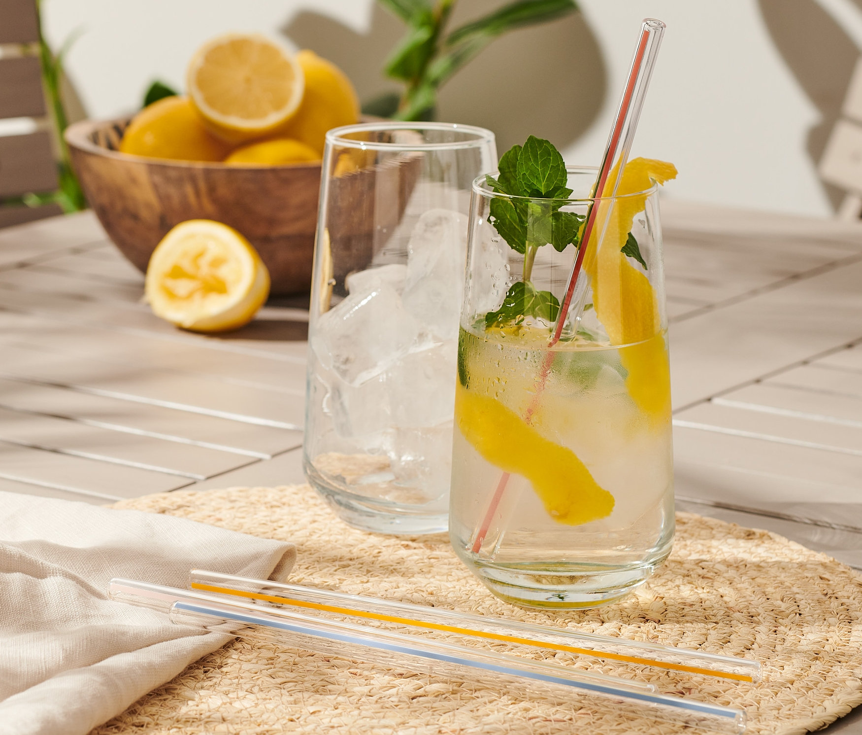Dva nápoje s citrónom a mätou na stole, vedľa drevená miska s citrónmi a Sklenené slamky, 4 ks.