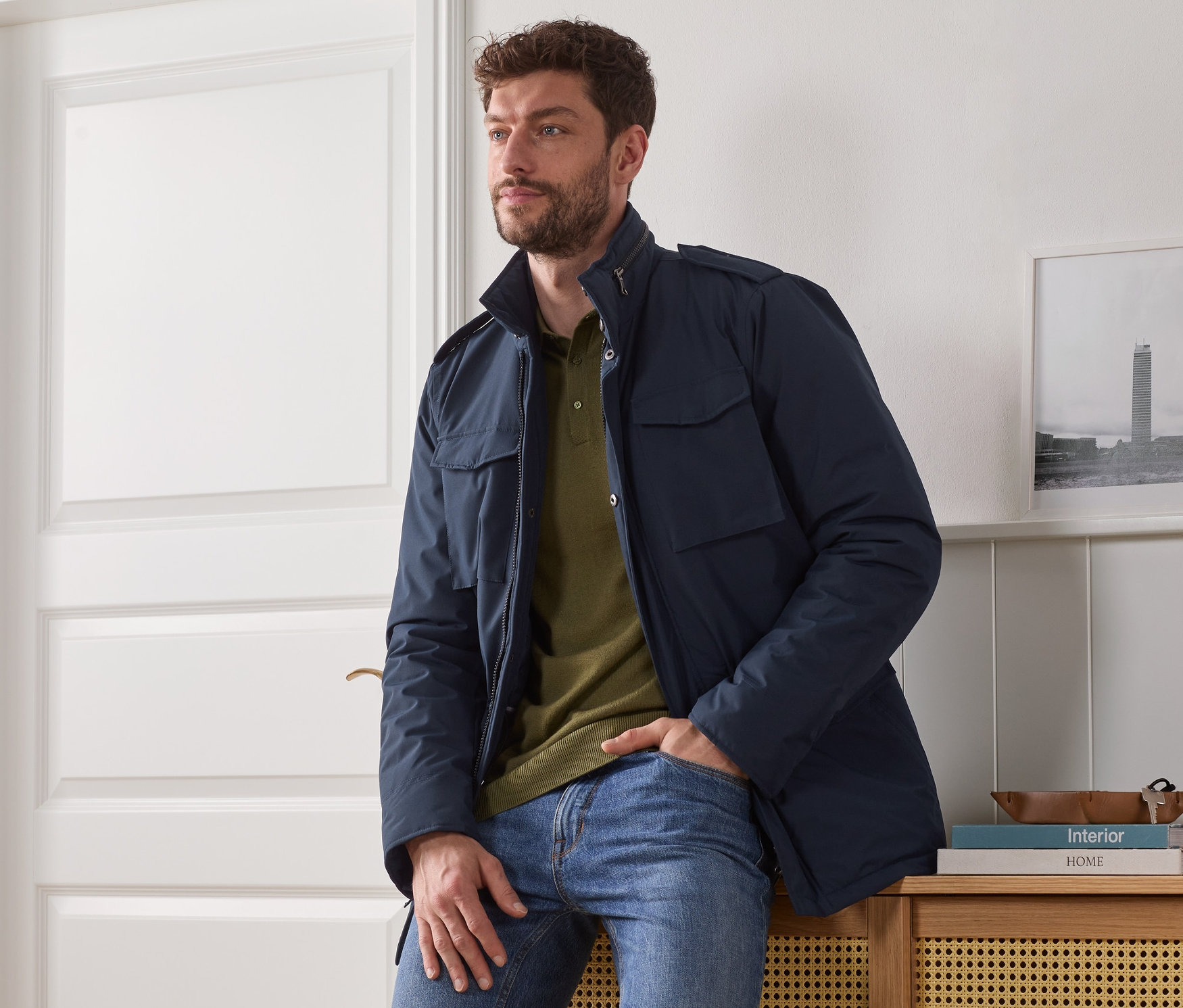 Muž sedí na skrinke a má na sebe modrú bundu.