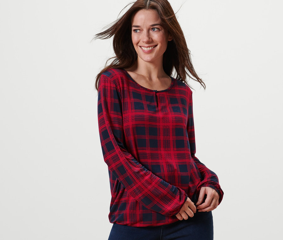 Usmievajúca sa žena pózuje v károvanom blúzkovom tričku.