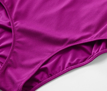 Detail fialových jednodielnych plaviek so štruktúrovaným povrchom.