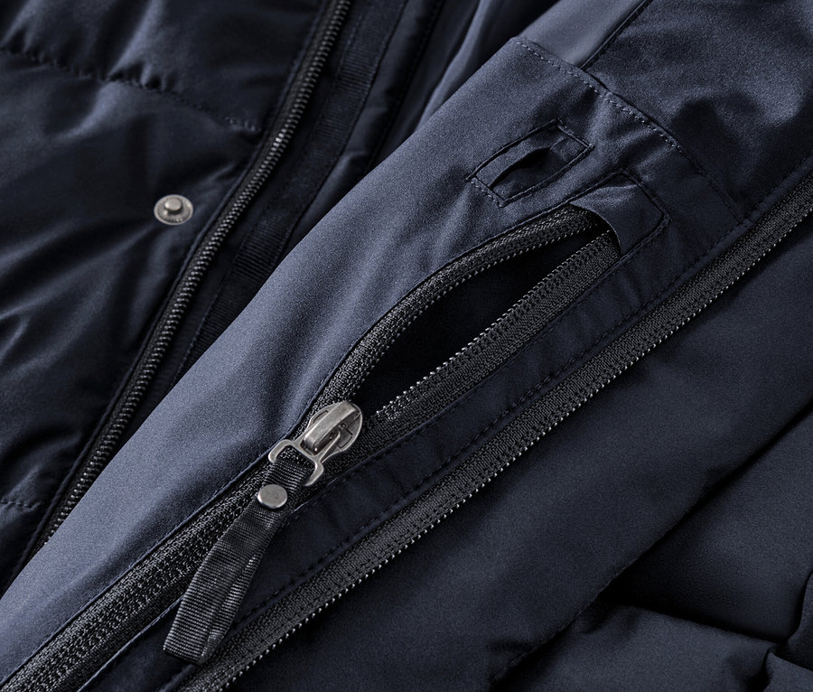 Detail modrej prešívanej parky s kapucňou, zips a gombíky.