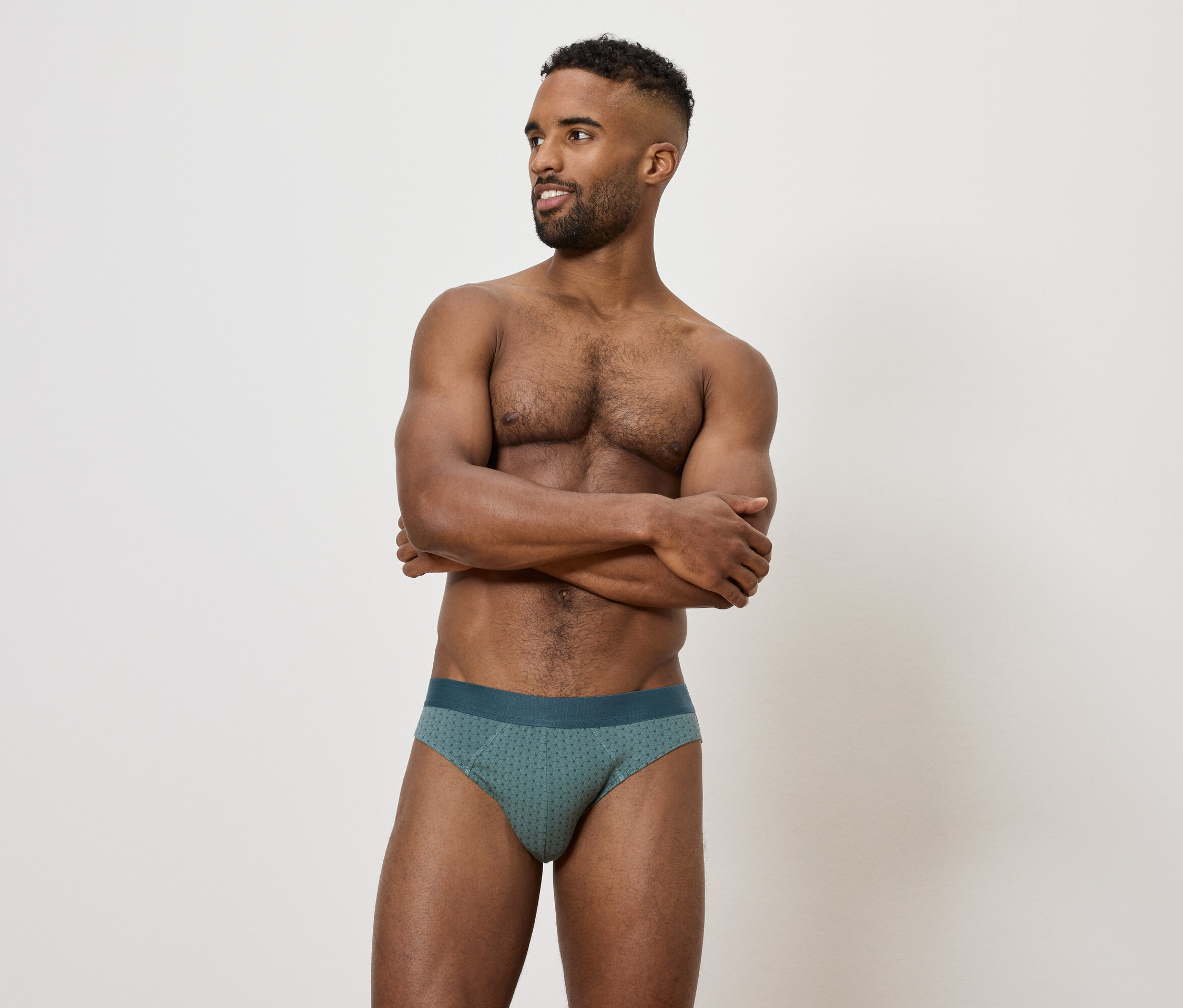 Muž so skríženými rukami na hrudi v zelených slipoch.