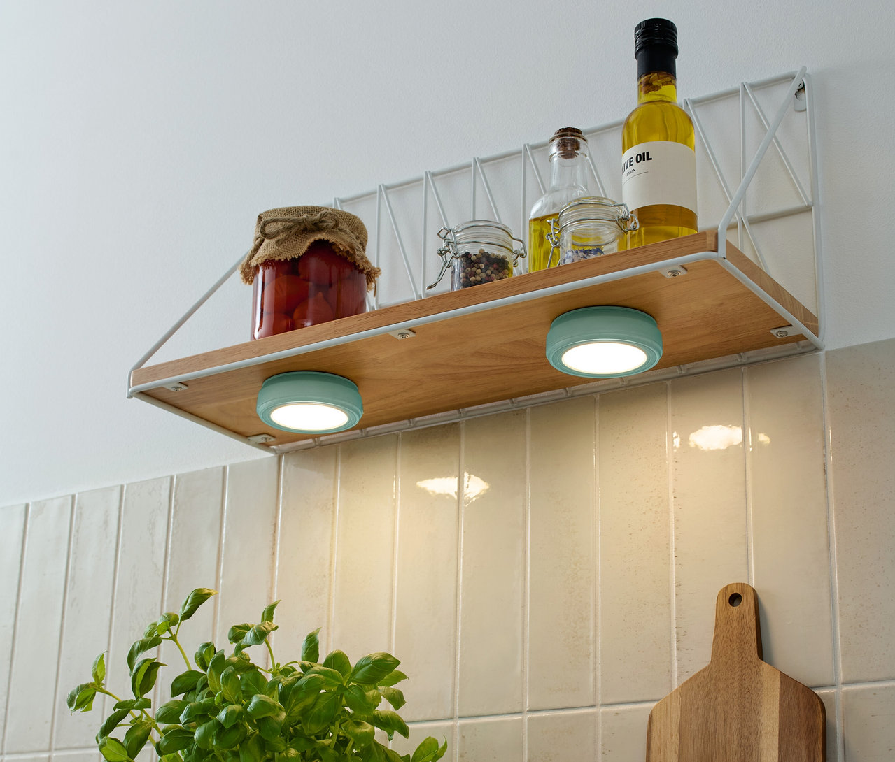 Na polici sú poháre s potravinami a fľaše s olejom, pod nimi sú dve tyrkysové 2 LED-Multifunktionsleuchten.