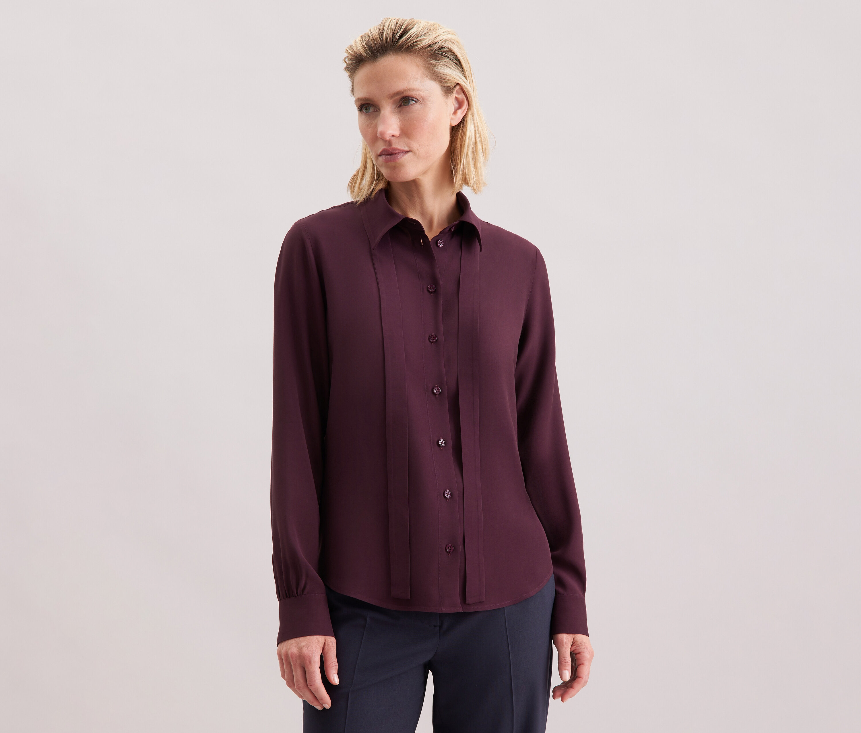 Žena má na sebe blúzku Seidensticker z viskózy, bordovú, s gombíkmi.