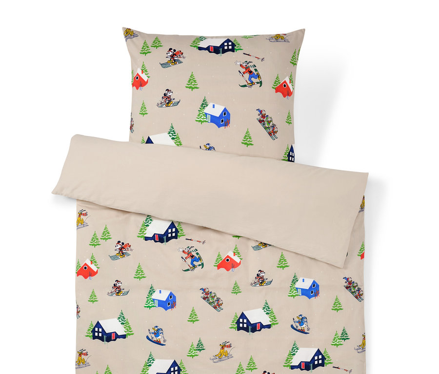 Posteľná bielizeň s potlačou zimnej krajiny s domami, stromami a lyžiarmi.