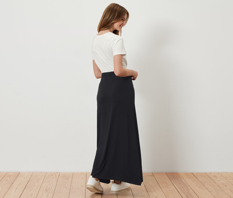 Žena má na sebe dlhú čiernu džersejovú sukňu.