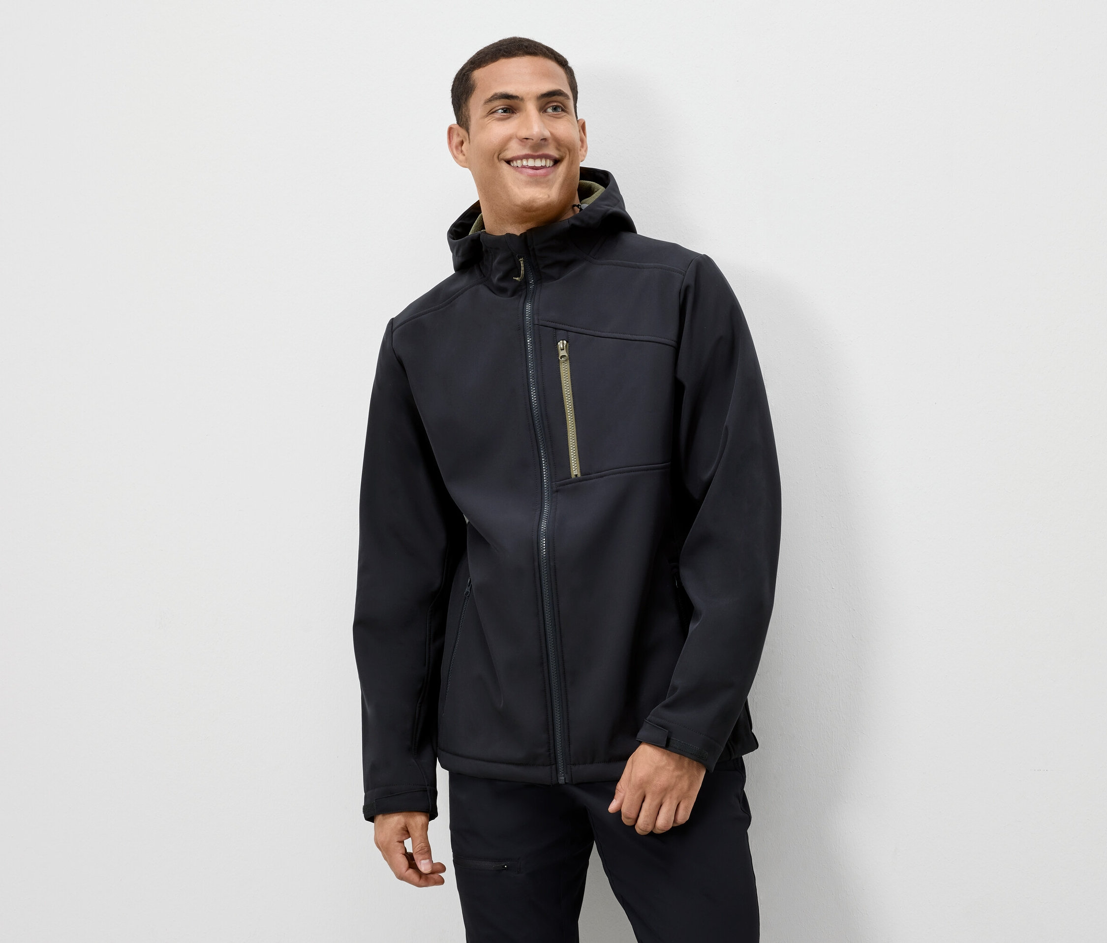 Muž sa usmieva a má na sebe čiernu bundu s kapucňou.