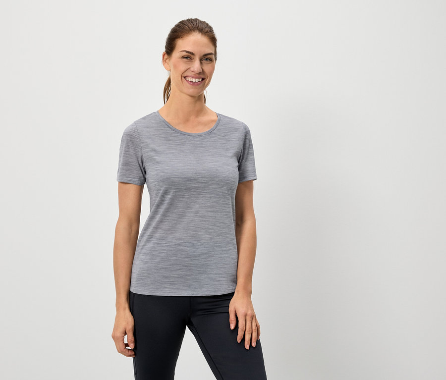 Žena má na sebe sivé tričko a čierne legíny.