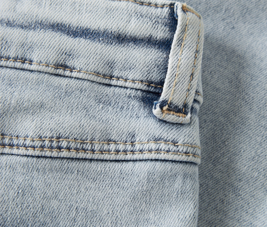 Detailný záber na svetlomodré džínsy s ružovou výšivkou srdca.