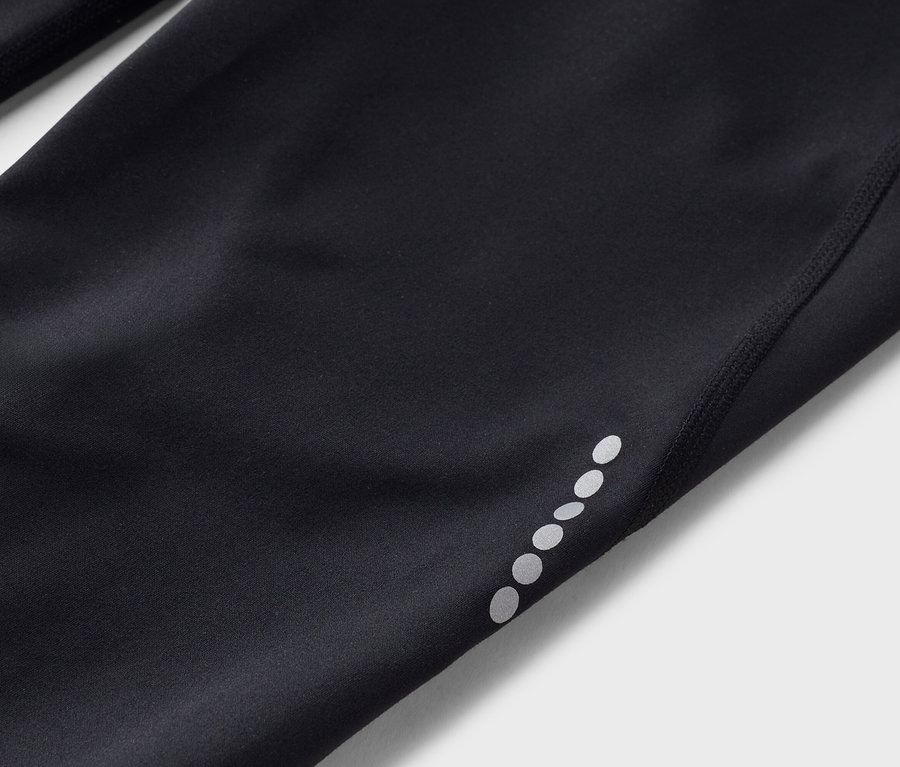 Detailný záber na čierne legíny s reflexnými bodkami na nohavici.