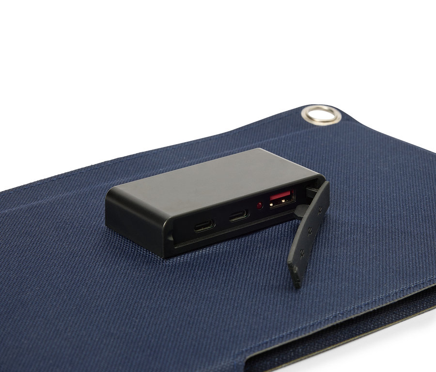 Čierna batéria leží na modrom povrchu látky, pričom je viditeľný USB port.