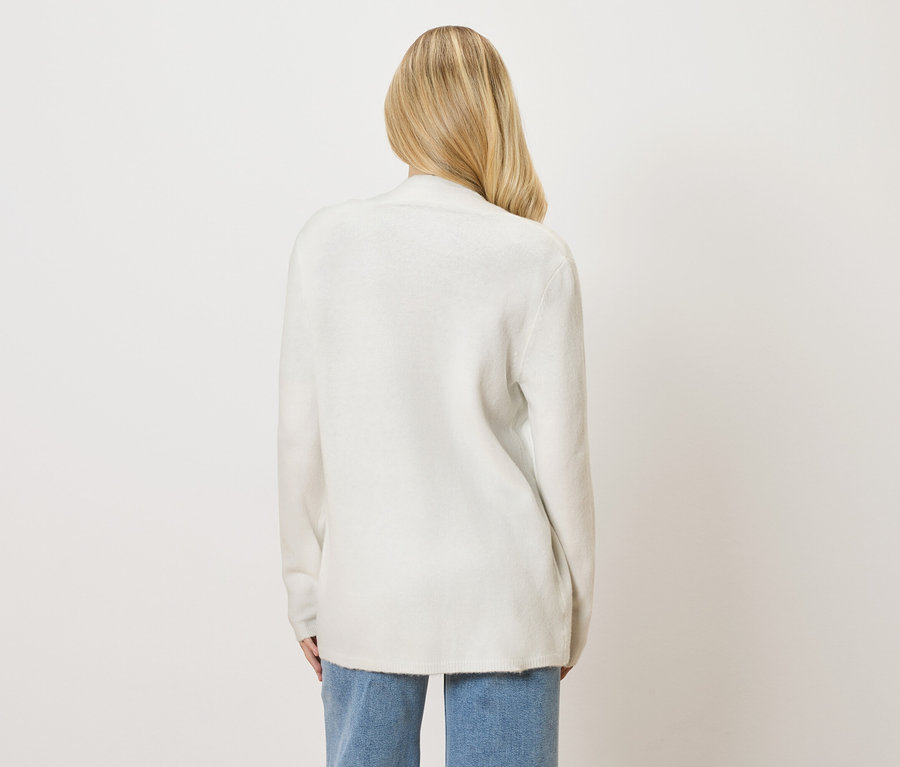 Pohľad zozadu na ženu s blond vlasmi v bielom kardigane a džínsoch.