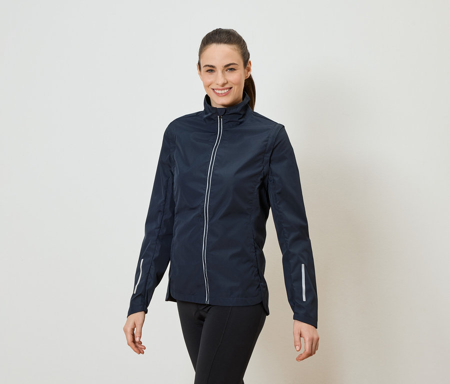 Žena s chvostom má na sebe tmavomodrú bundu na zips a čierne legíny.