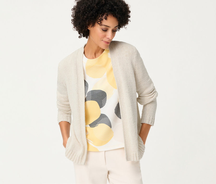 Žena s ľanovým kardigánom Olsen cez tričko so žltými a sivými kruhmi, má ruky vo vreckách.