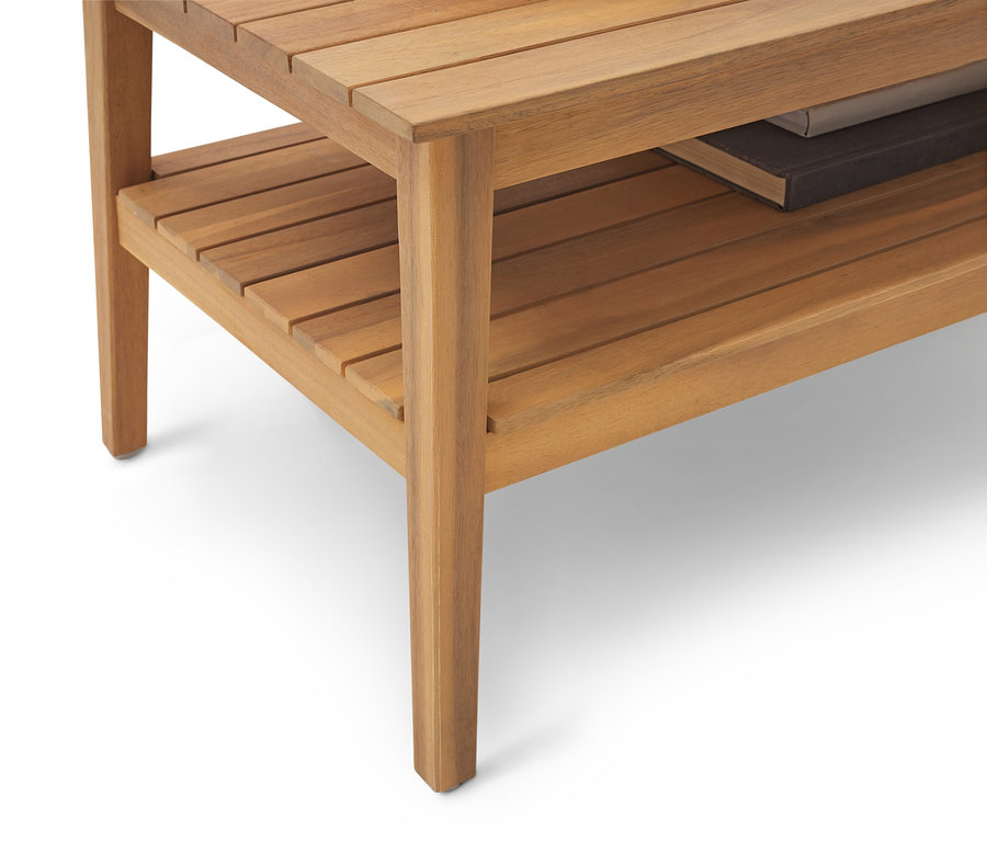 Detailný záber na svetlohnedý drevený príručný stolík s poličkou a knihou.