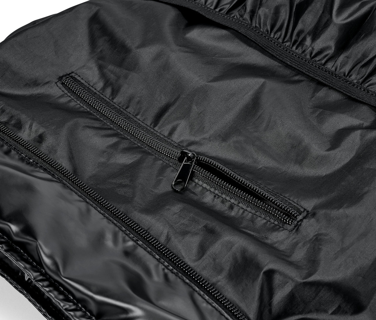 Detail lesklého čierneho odevu so zipsami.