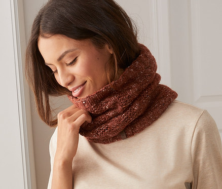 Žena si upravuje pletený dutý šál na krku.