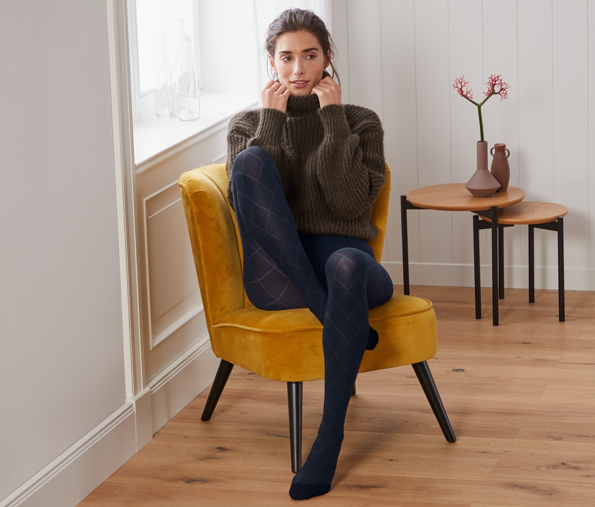 Žena sedí v kresle a má na sebe jemné pančuchové nohavice s károvanou štruktúrou.