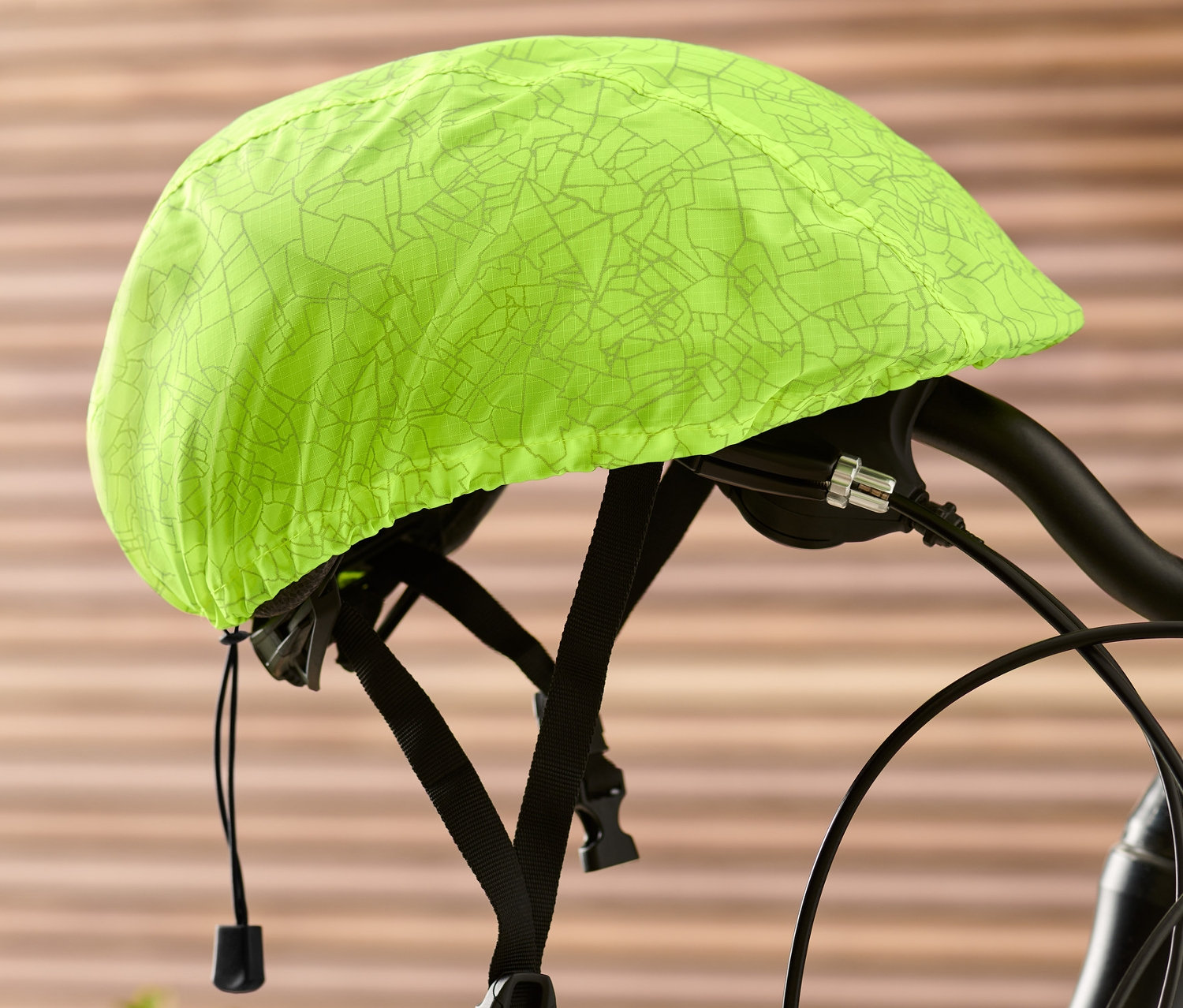 Na riadidlách bicykla je nasadený neónovo žltý obal na cyklistickú prilbu.