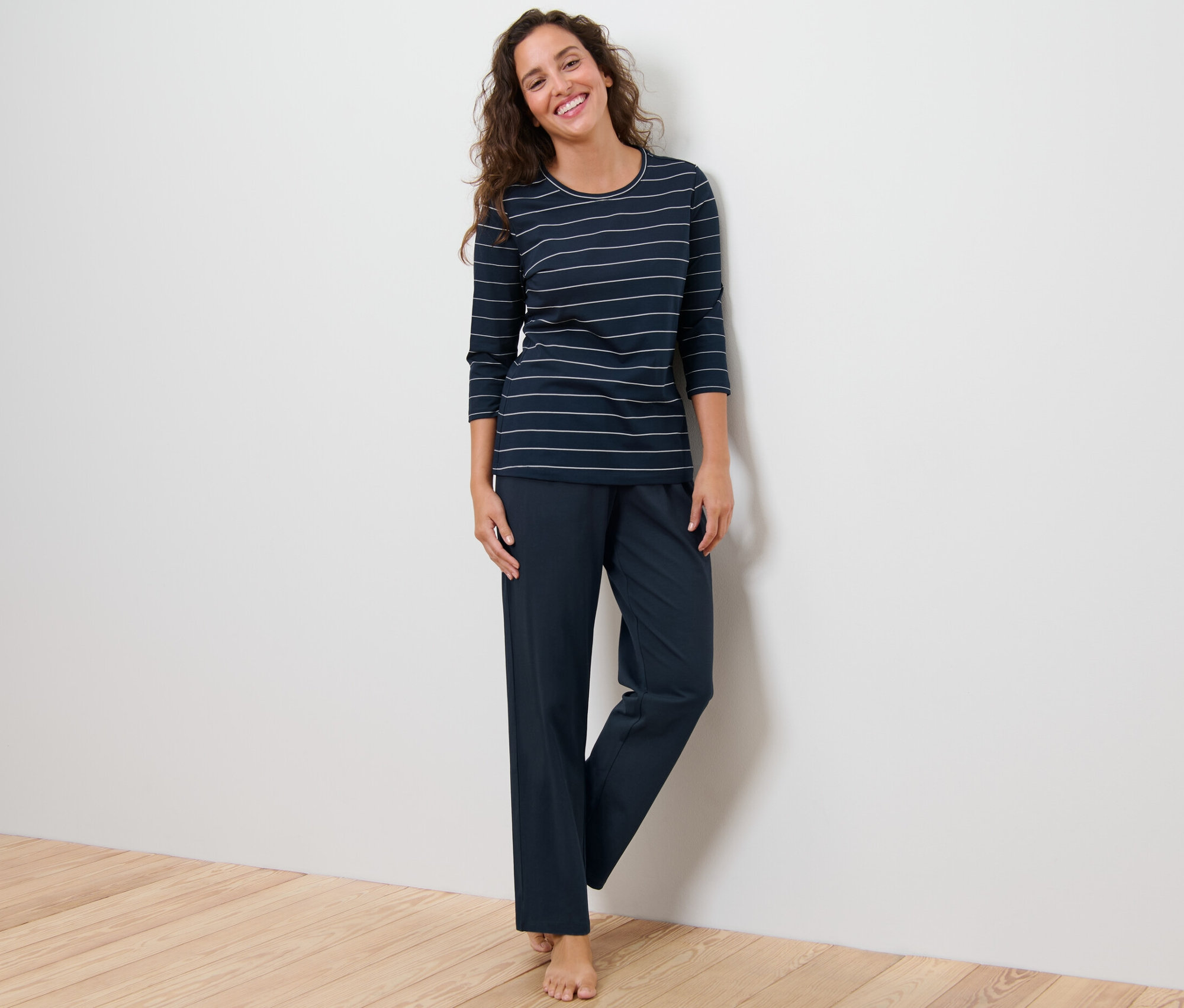 Žena stojí a má na sebe pyžamo s prúžkami.