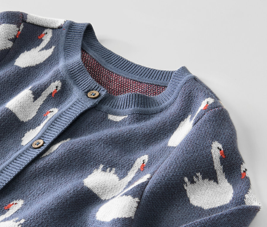 Detail modrého detského svetríka s labuťami.