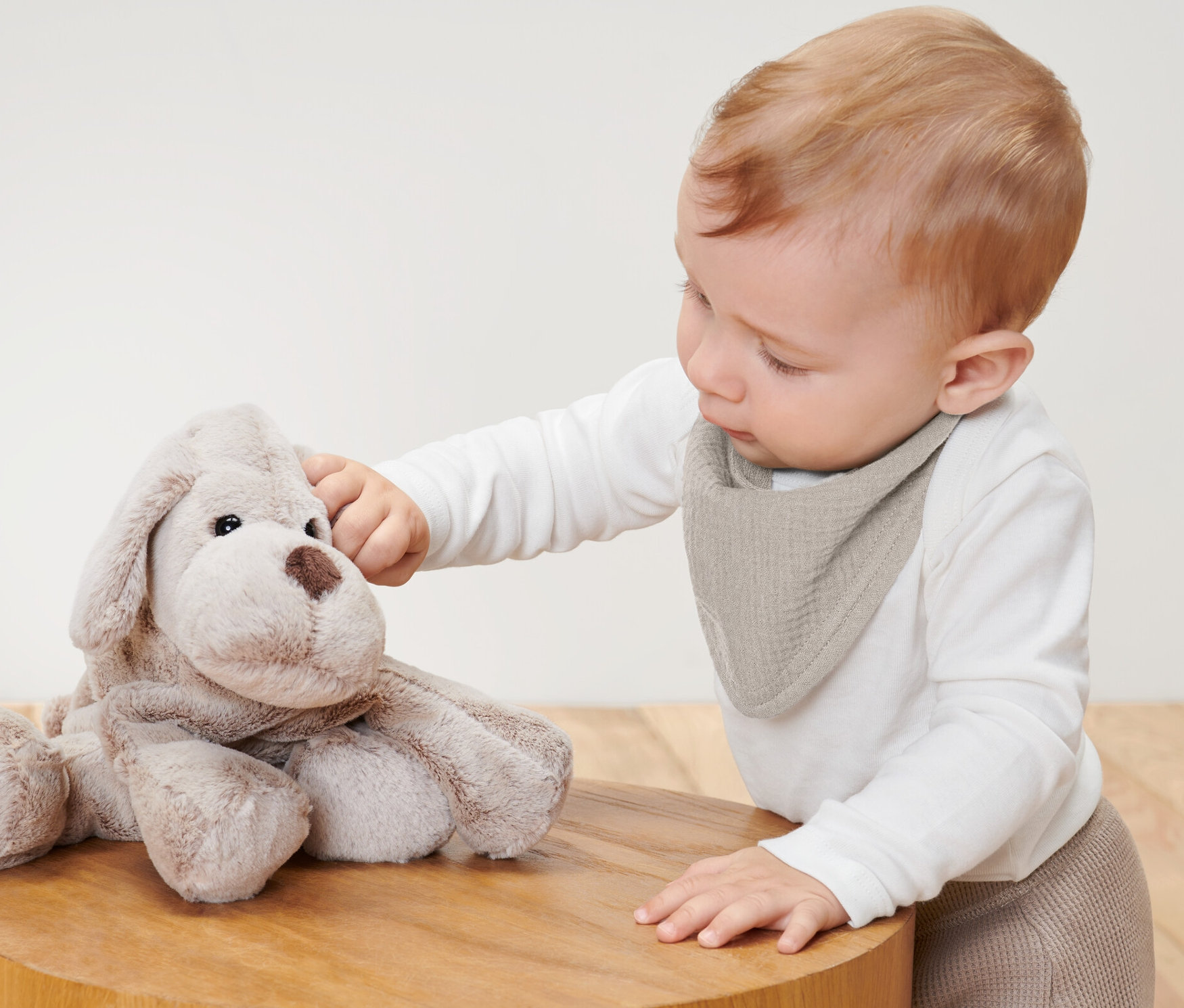 Dieťa sa dotýka plyšového psa a má na sebe detské mušelínové šatky na krk, 2 ks.