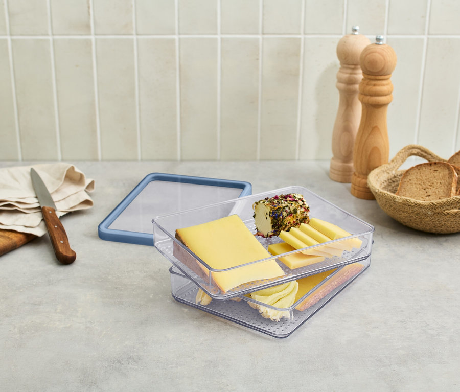 Poschodová dóza na potraviny so syrmi a údeninami na stole.