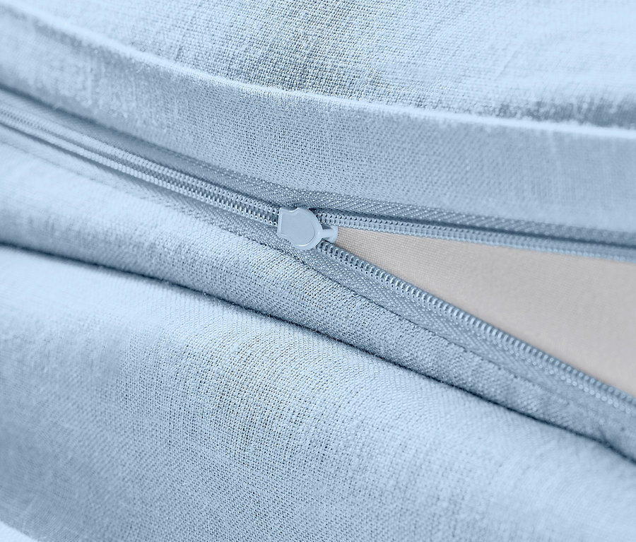 Detail svetlomodrej ľanovej posteľnej bielizne štandardnej veľkosti so zipsom.