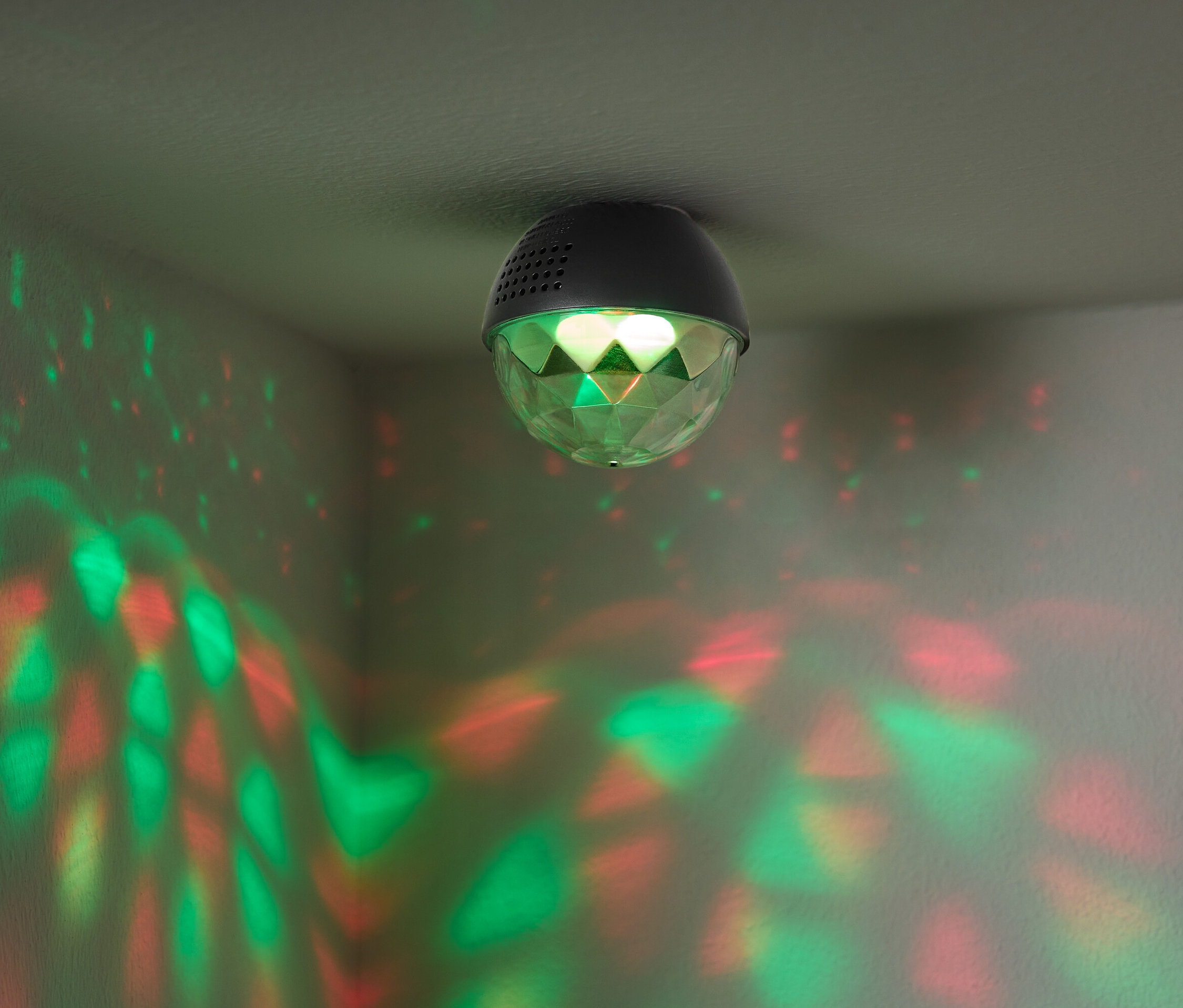 Disko guľa pripevnená k stropu vrhá na steny červené a zelené svetlo.