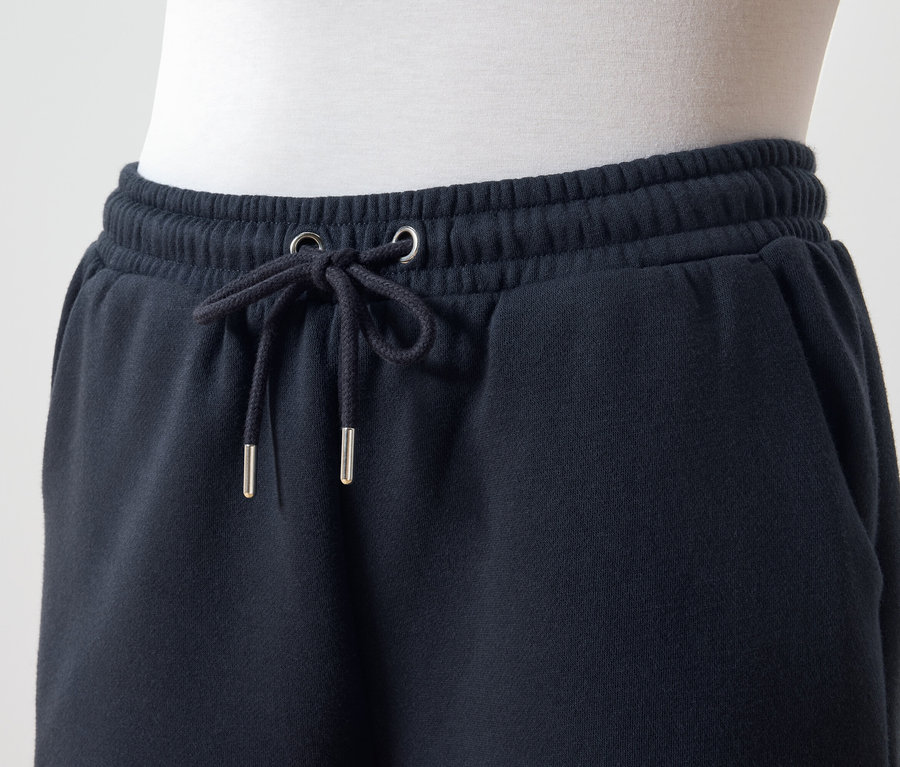 Detail tmavomodrých teplákov so šnúrkou v páse.