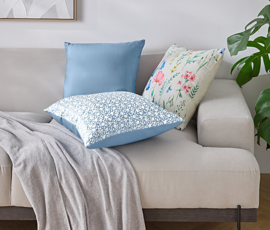 Na pohovke sú tri vankúše a deka.