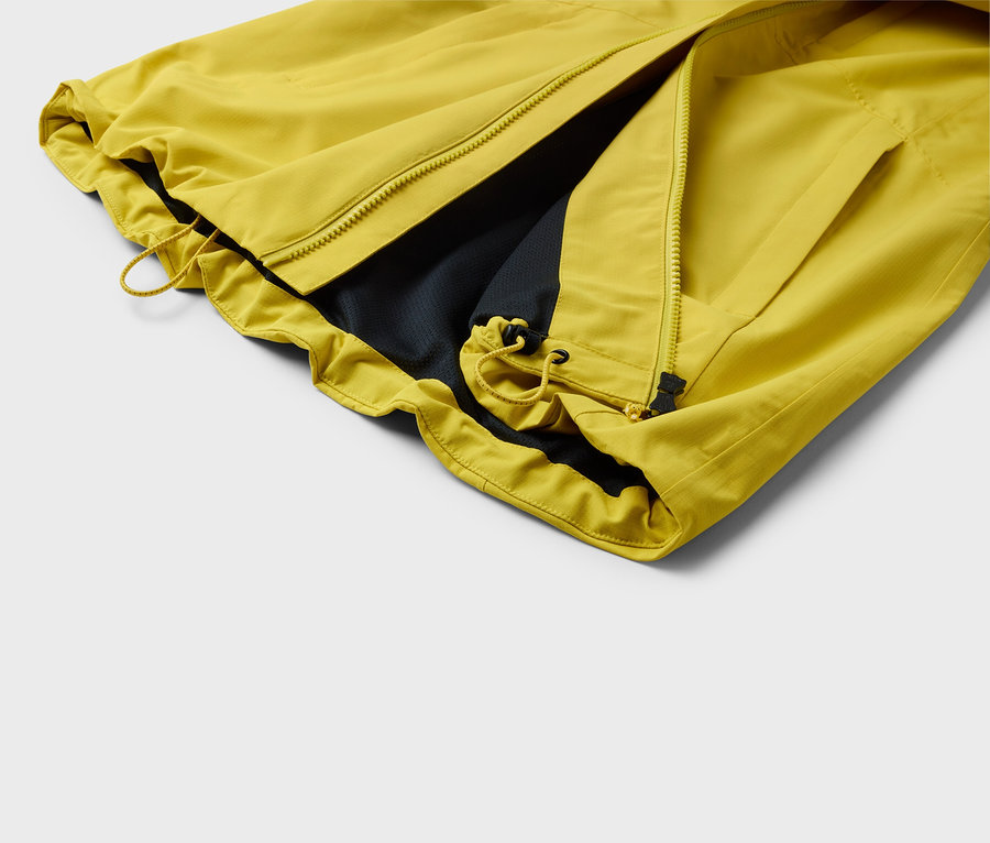 Detail žltej bundy s rozopnutým zipsom a čiernou podšívkou.