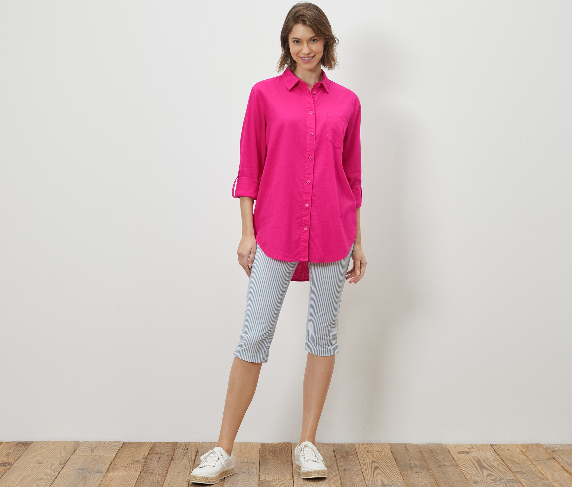 Žena stojí a má na sebe dlhú ľanovú blúzku ružovej farby.