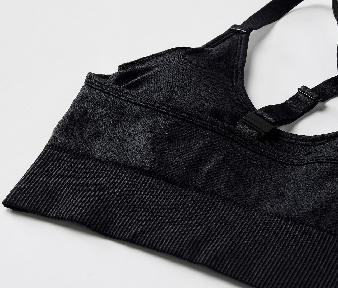 Detailný záber na čiernu športovú podprsenku s nastaviteľnými ramienkami a rebrovaným lemom.