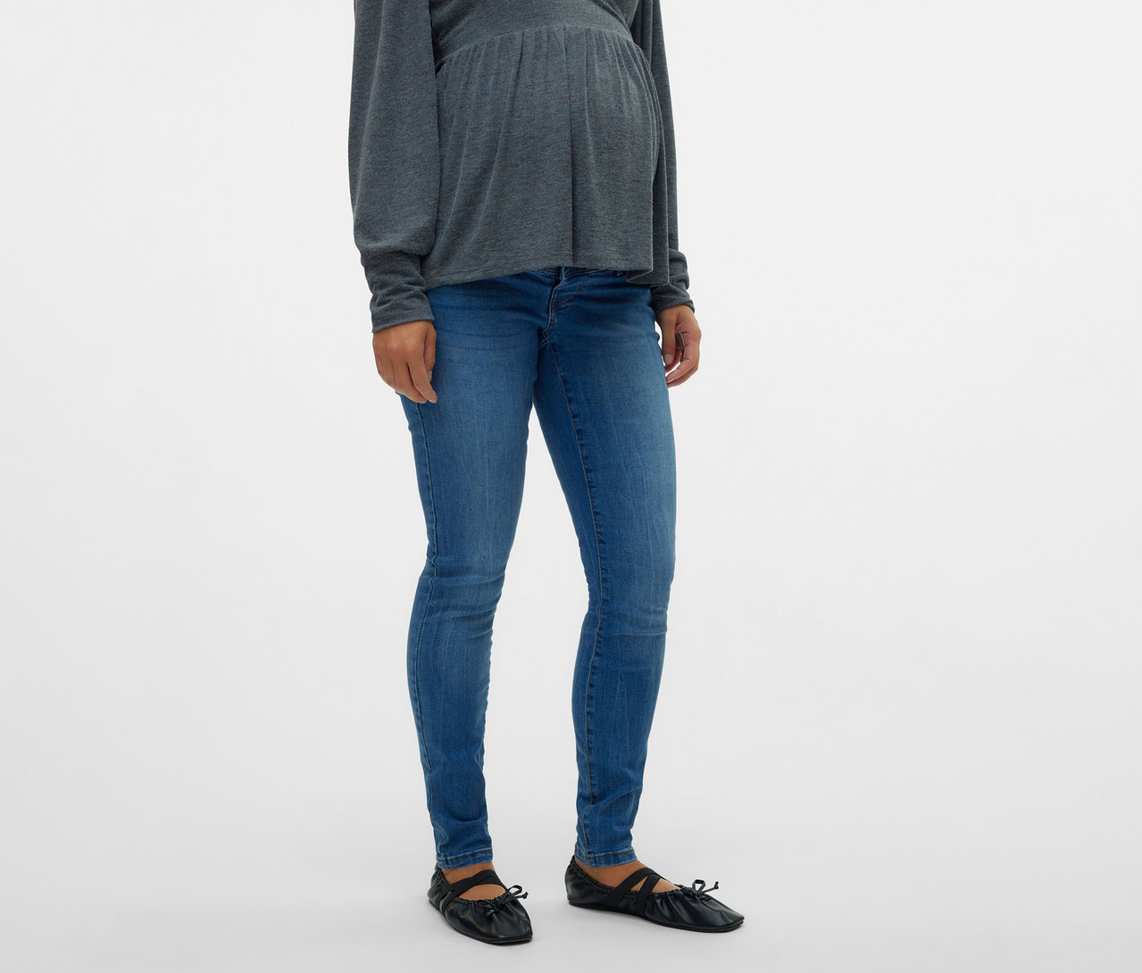 Tehotná žena má na sebe sivý top a skinny džínsy MAMALICIOUS »MLMILA« a čierne balerínky.