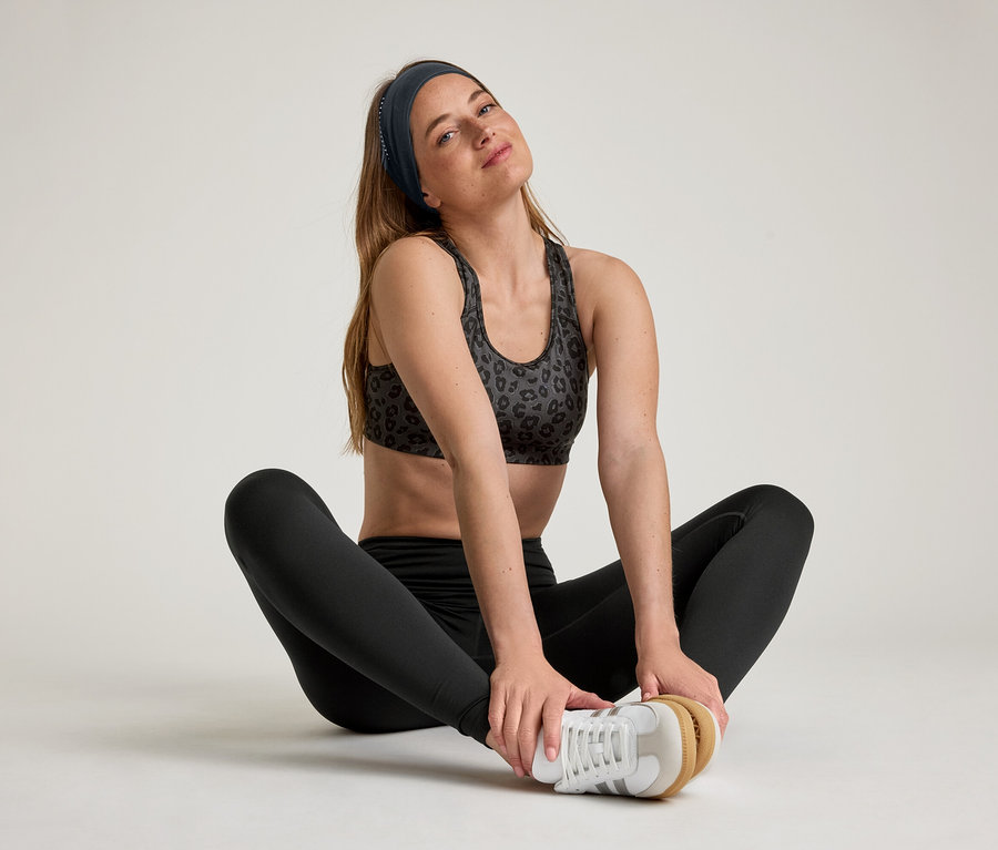 Žena sedí s rozkročenými nohami a má na sebe športové legíny »ActiveSoft«.
