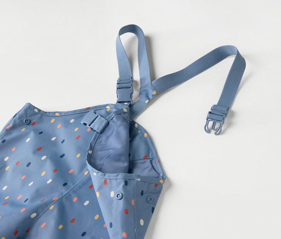 Modrá detská zástera s farebnými bodkami a modrými ramienkami na bielom pozadí.