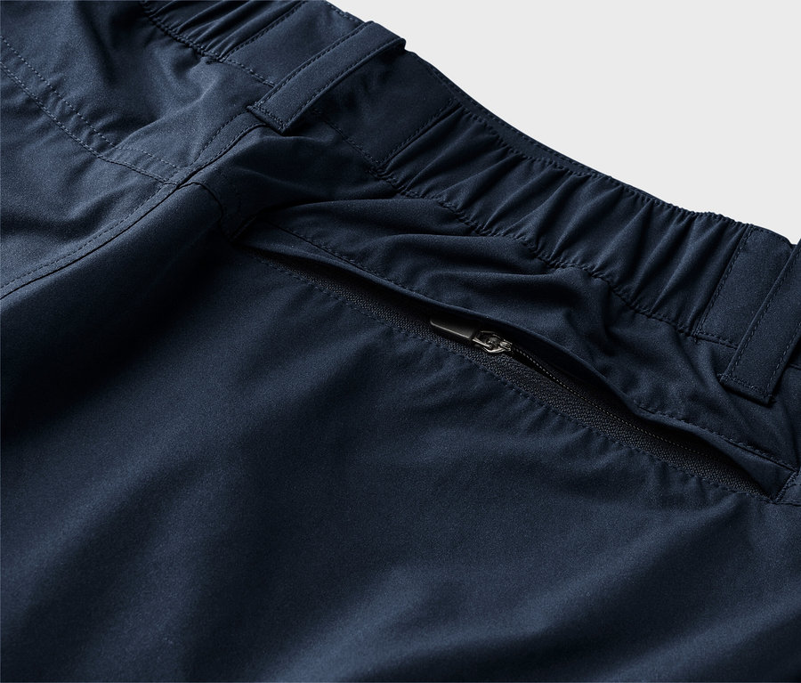 Detailný záber na tmavomodré nohavice s elastickým pásom a vreckom na zips.
