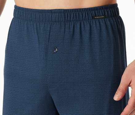 Muž má na sebe modré voľné trenírky s gombíkom.