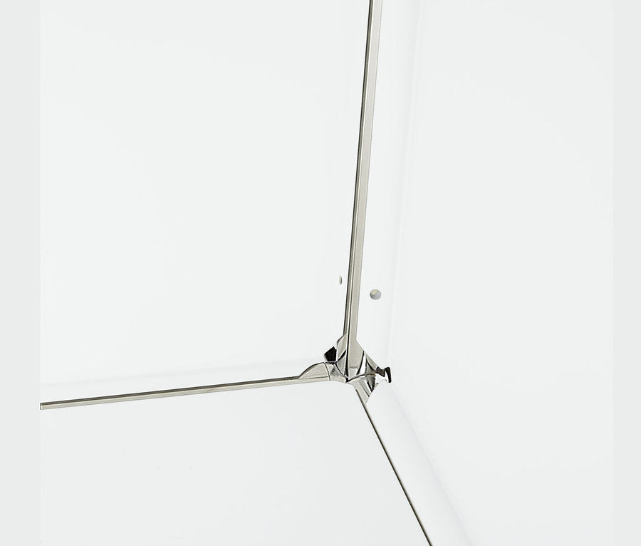 Detail rohu bielej kovovej odkladacej skrinky s 2 nastaviteľnými výklopnými priehradkami.